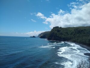 On the left is a clear, blue ocean. On the right is a coastline of green, lush valleys and white surf.